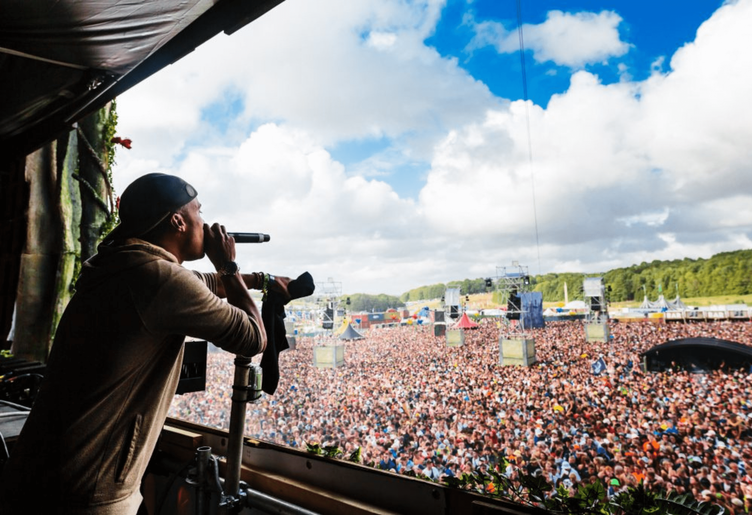 Man with microphone singing in front of large crowd at a festival