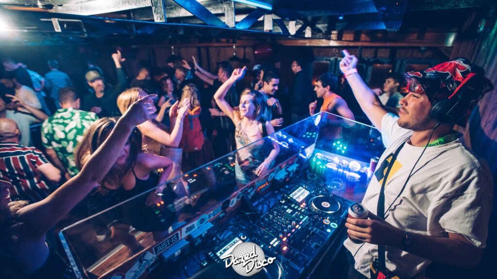 Dj in front of mixing desk with an audience dancing