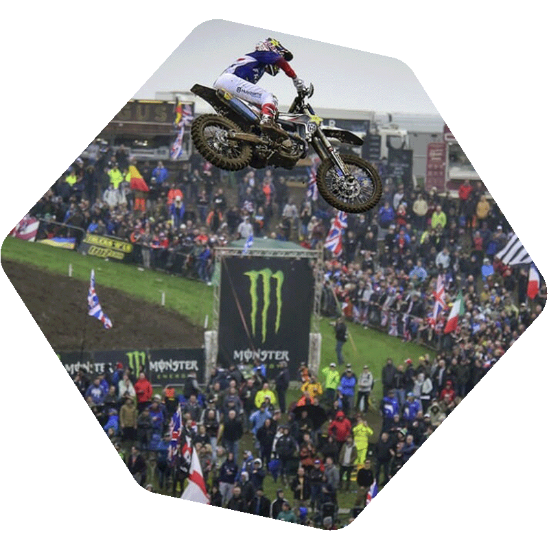 Motocross rider in the air with a crowd of people in the distance