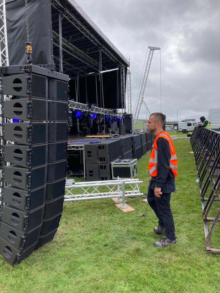 A man in a high-viz stood in front of stacked speakers