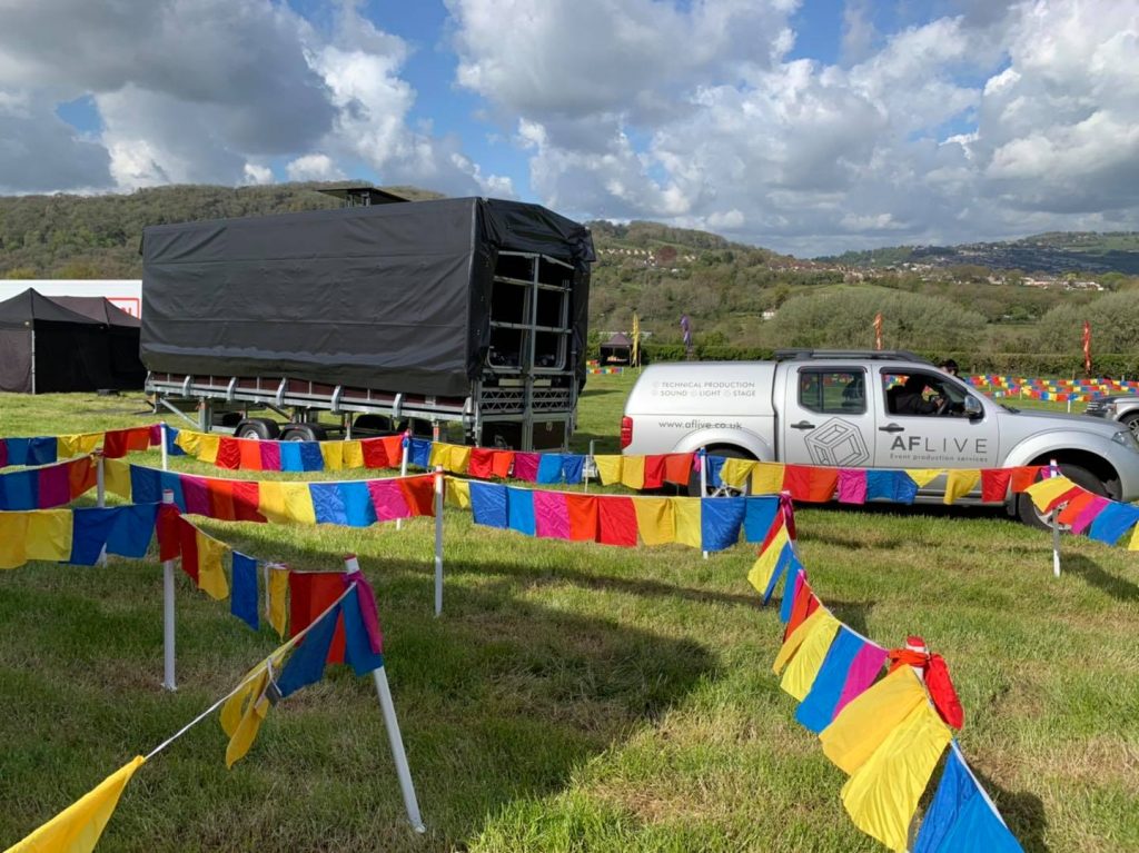 AF Live truck towing a trailer on grass behind colourful flags